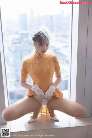 A woman in a yellow dress talking on a cell phone.