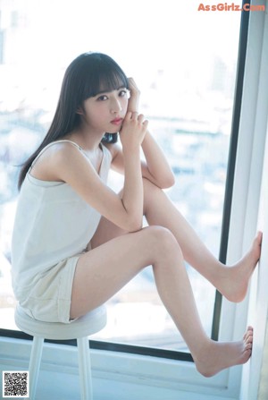 A woman sitting on top of a bed next to a window.