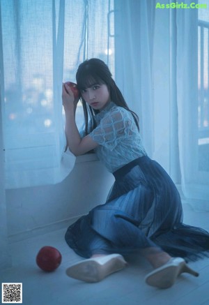 A woman sitting on top of a bed next to a window.