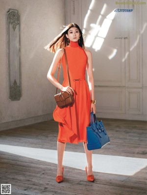 A woman in a black dress holding an orange purse.