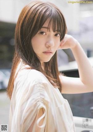 A woman with long brown hair and bangs is posing for a picture.