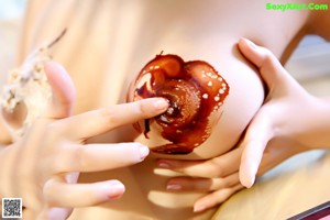 A woman holding a piece of ice cream in her mouth.