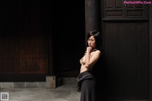 A naked woman sitting on a stool in a room.