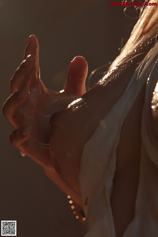 A close up of a woman's hand with water droplets on it.