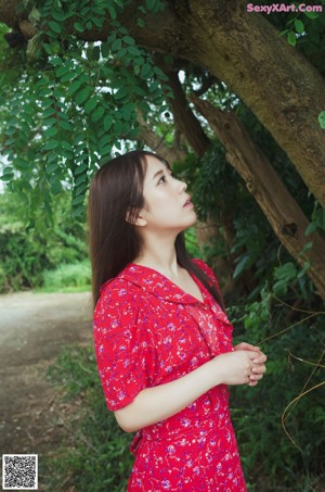 A naked asian woman leaning against a wooden fence.