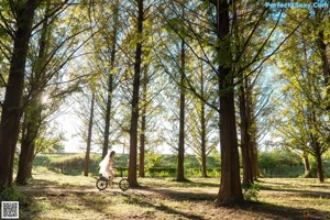 A woman in a white dress is walking through the woods.