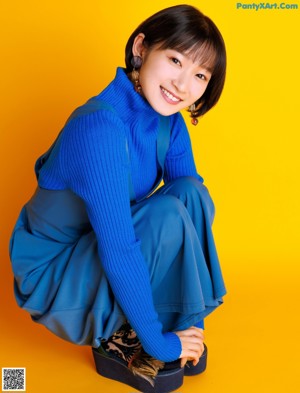 A woman in a blue turtle neck sweater posing for a picture.