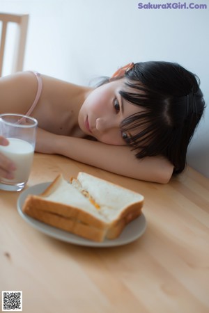 A woman sitting on a couch eating a piece of bread.