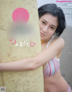 A woman in a bikini holding a surfboard on the beach.