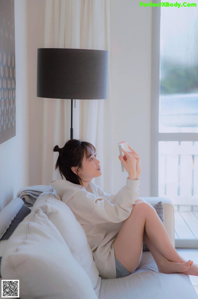 A woman sitting on a couch holding a cell phone.