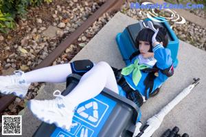 A woman in a blue and white outfit sitting on a train track.