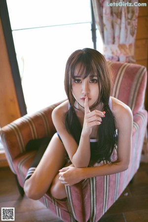 A woman sitting on a wooden deck next to a pool.