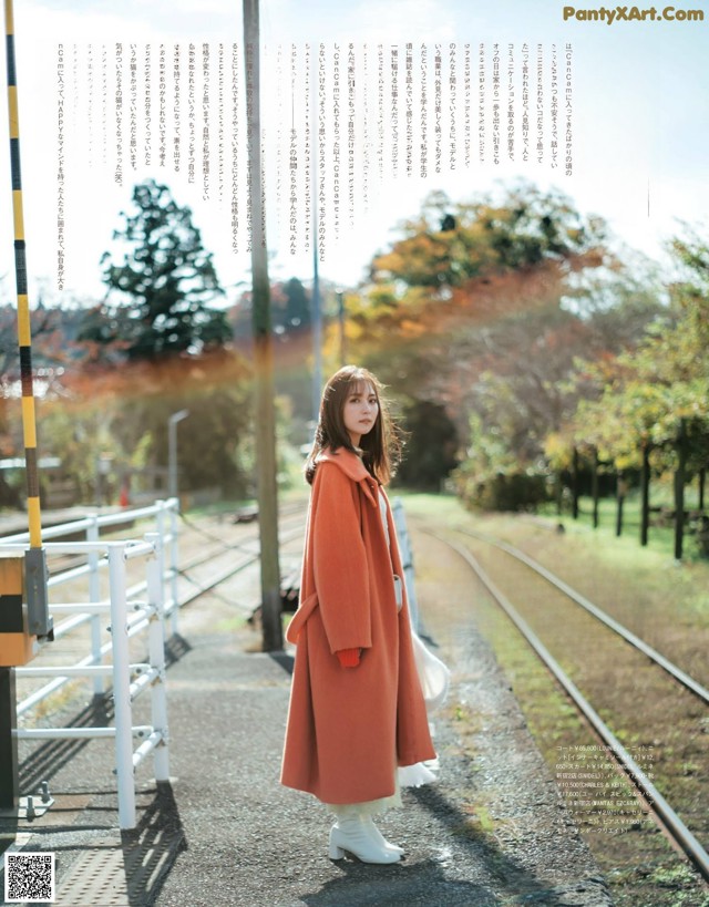 A woman in a red coat standing on a train track.