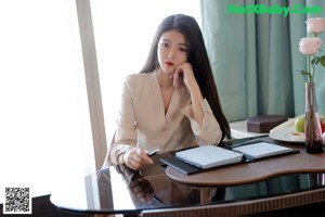 a woman standing in front of a table with a laptop