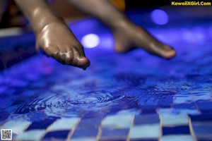 A woman sitting on the floor next to a swimming pool.