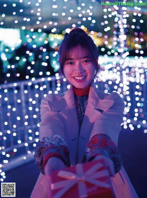 A woman holding a present in front of a city at night.