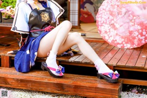A woman sitting on a wooden bench holding a cell phone.