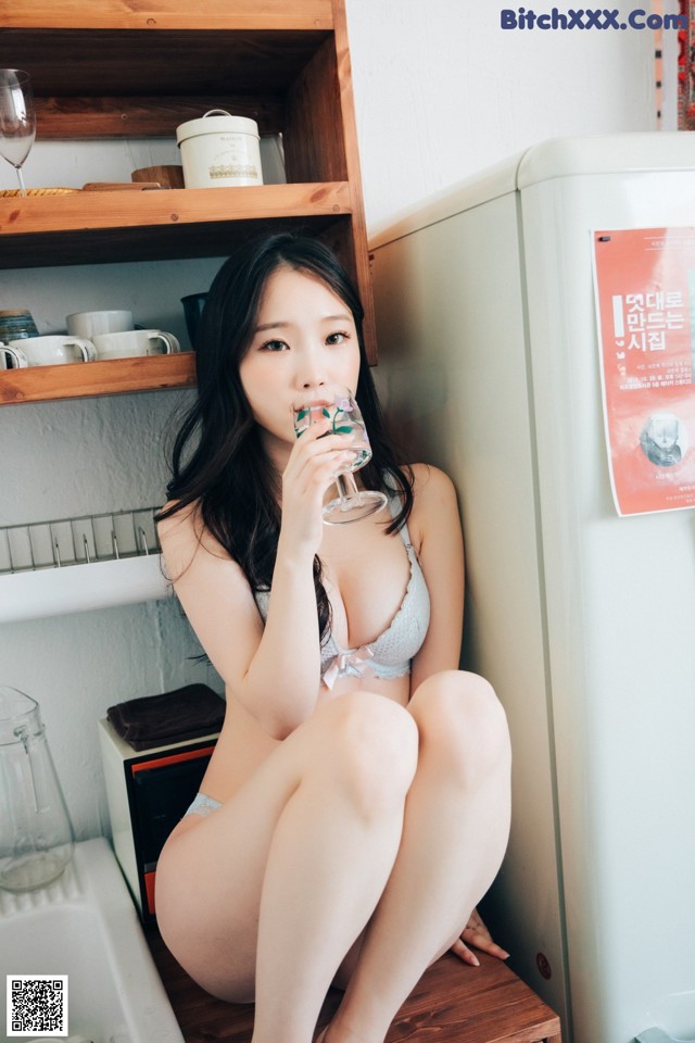 A woman sitting on top of a wooden box holding a glass of wine.