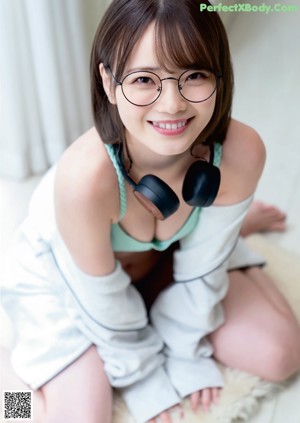 A woman in a white shirt and skirt posing on a couch.