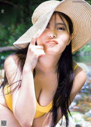 A woman in a bikini holding an inflatable elephant on her head.