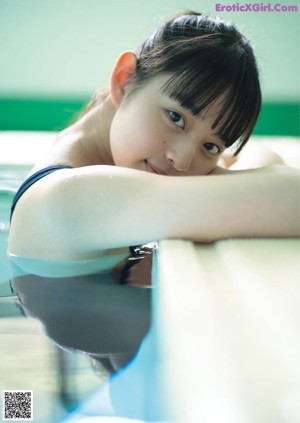 A woman in a white bra and panties leaning against a wall.