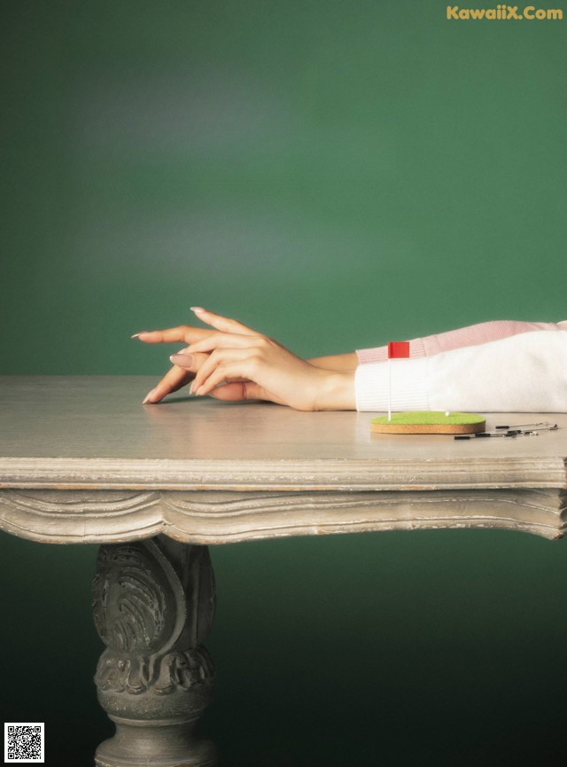 A woman's hand on a table with a green background.