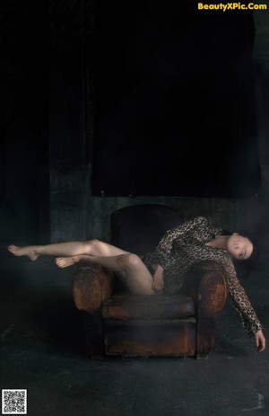 A naked woman laying on a bed in front of a window.