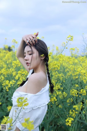 A woman standing in a field of yellow flowers.