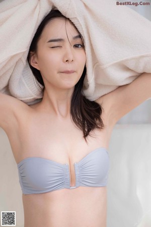 A woman in a white sweater and gray panties posing for a picture.