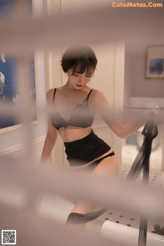 A woman in a black lingerie standing in front of a mirror.