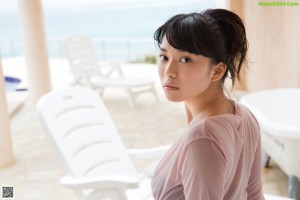 A woman in a pink robe sitting on a bathtub.