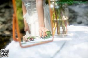 A woman in a white dress is reflected in a mirror.