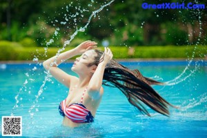 A woman in a bikini posing by a swimming pool.