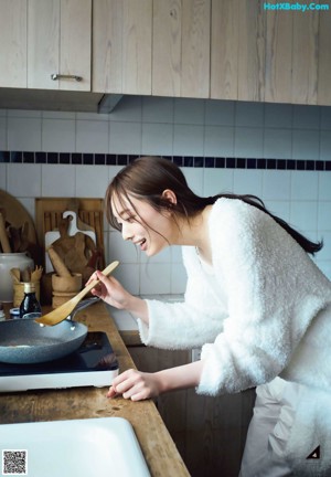 A woman sitting in front of a window wearing a white robe.