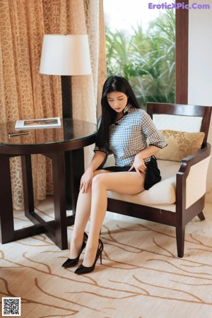 A woman in a black dress sitting on a table.