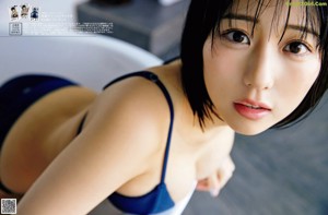 A woman in a blue bikini sitting on a bed.