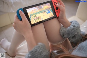 A woman in a blue sweater and white stockings posing on a couch.