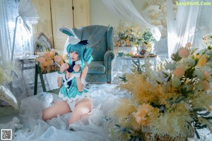 A woman in a blue and white outfit sitting on a blue chair.