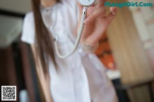 A woman in a nurse outfit is posing on a bed.