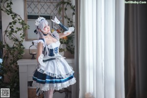 A woman in a maid outfit sitting on a window sill.