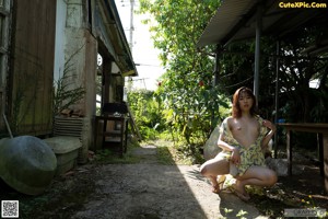 A naked asian woman posing in front of a bush.