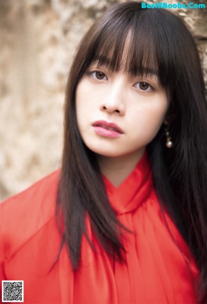 A woman with long black hair wearing a red shirt.