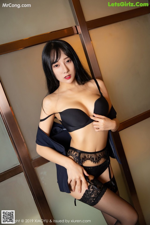 A woman in a black lingerie posing for the camera.