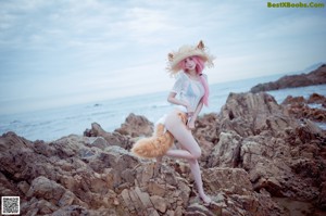 A woman in a bikini standing on a rocky beach.