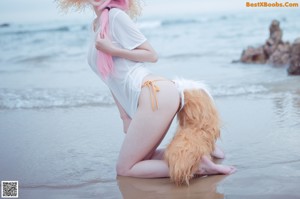 A woman in a white dress and a straw hat on a beach.