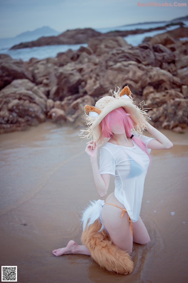 A woman in a bikini and a cat hat on the beach.