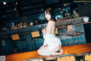 A woman standing in front of a bar wearing stockings.