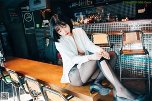 A woman sitting at a bar with a drink in her hand.