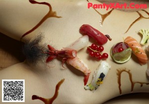 A naked woman laying on a table covered in sushi.