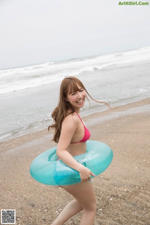 A woman in a pink bikini standing on a beach.